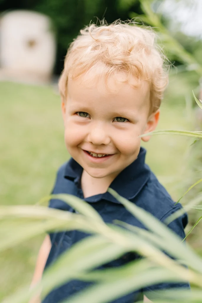 Kindergarten Fotografie Junge hinter Busch