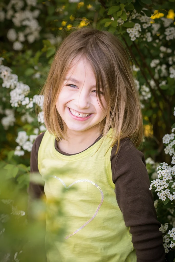 Mädchen vor Busch mit weißen Blüten